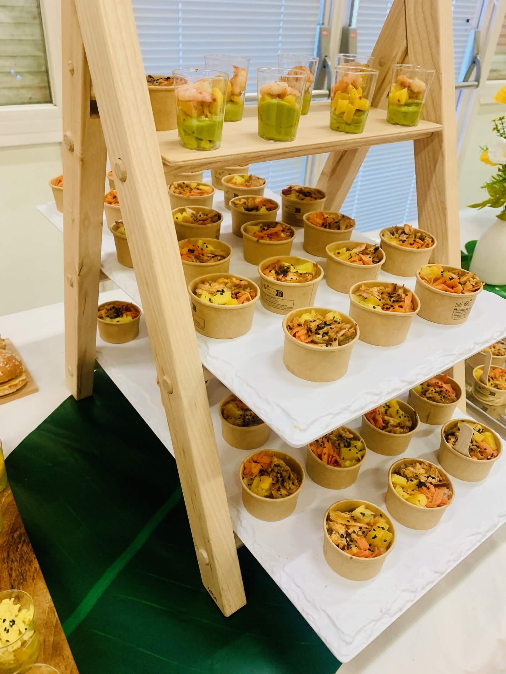 Verrines crevette, mangue et avocat et petits pots de salade présentés sur un support en bois pour un vin d'honneur