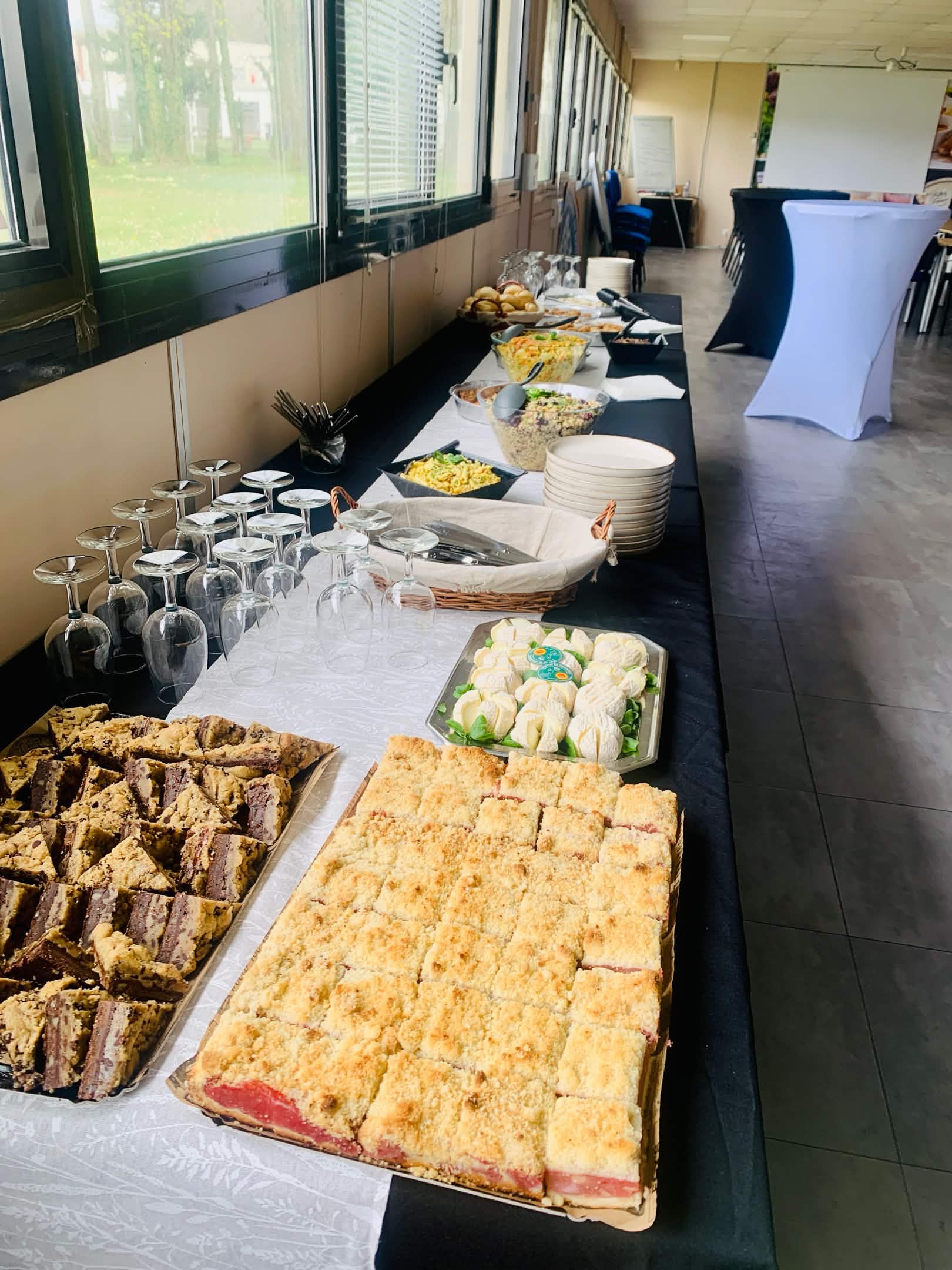Buffet dressé dans une salle : salades composées, plateau de fromages, crumble et desserts maison